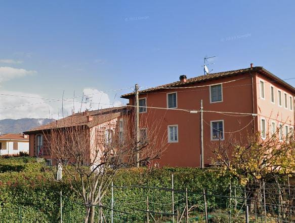 Condominio Castelli: il fabbricato toscano ristrutturato, con la facciata in tinta rossa e le persiane chiare.