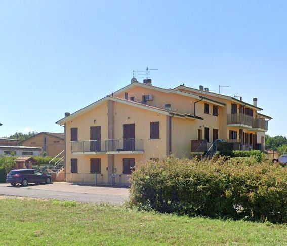Condominio Tau visto dal prato, con i balconi in linea e le ville a schiera sul lato destro.