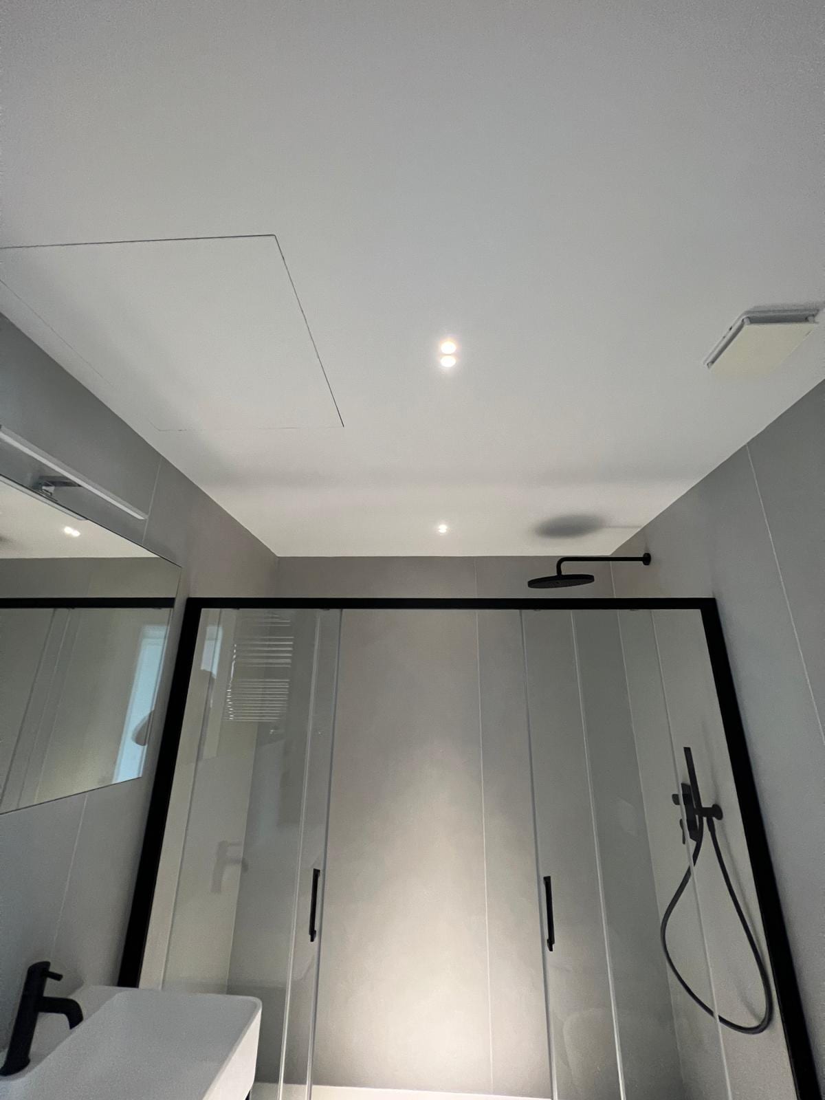Bagno di FRAME con box doccia in cristallo, soffione a parete e rivestimento in gres di grande formato.