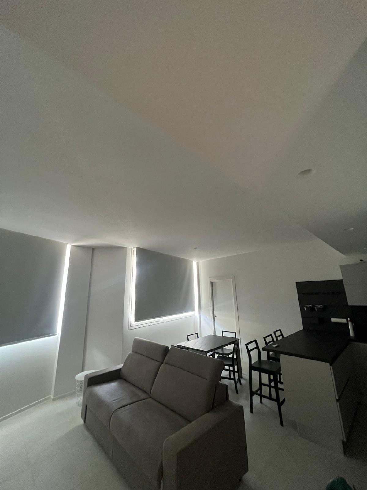 Soggiorno di FRAME con il taglio di luce continuo lungo il perimetro del controsoffitto.