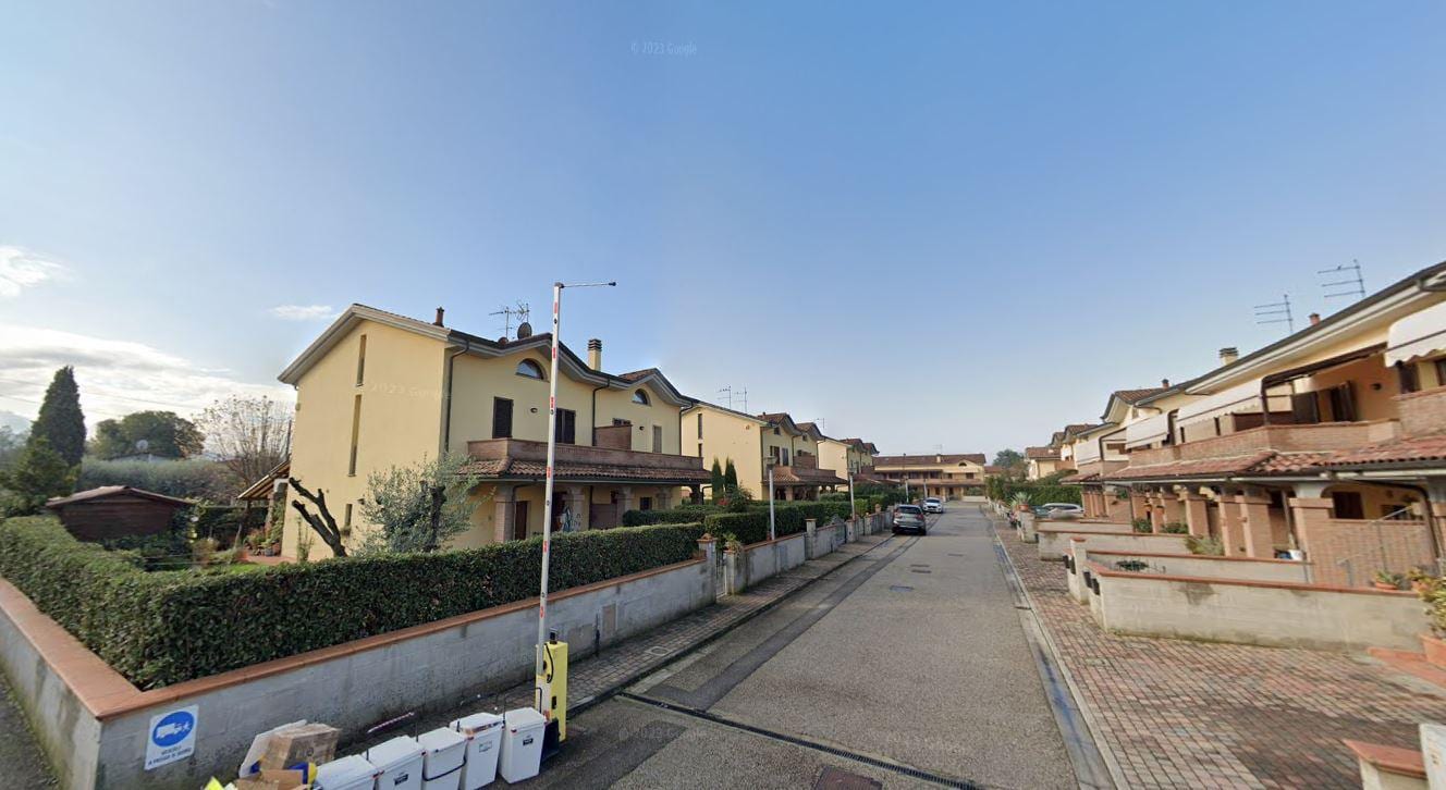Le Fresie: il fronte di una schiera con il portico in laterizio e la siepe che accompagna la via.
