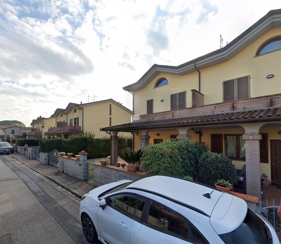 Una schiera di Le Fresie vista dalla strada, con il portico in laterizio e le aiuole davanti agli ingressi.