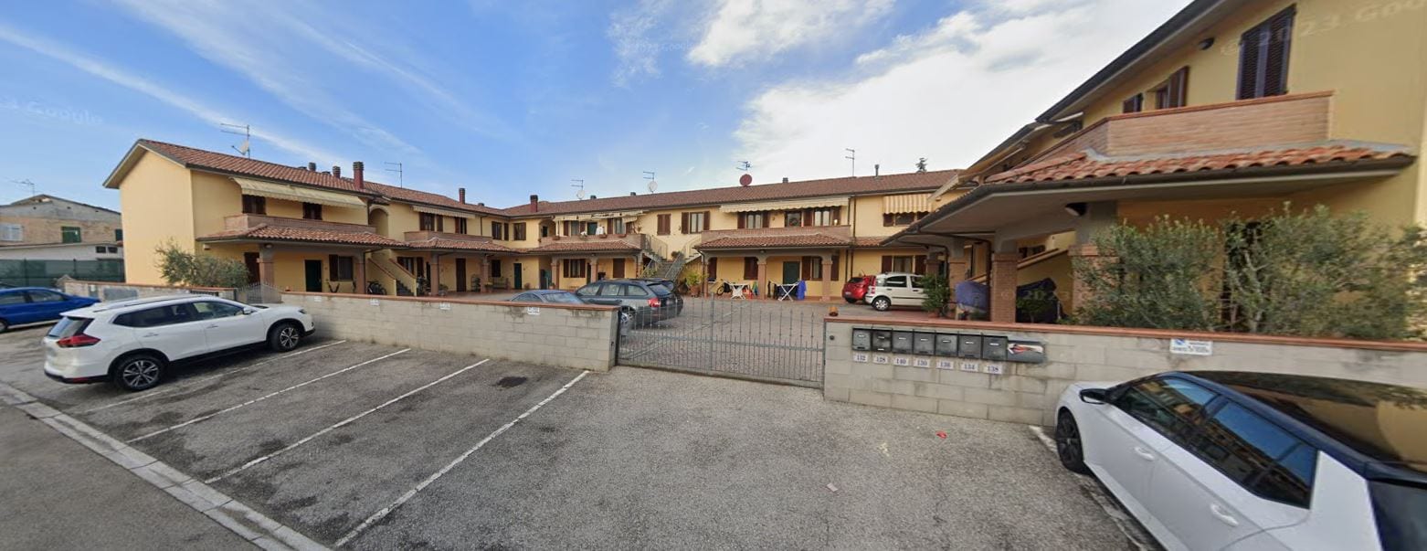 Il fronte lungo di Quartiere U, con le logge in linea, le scale esterne e il parcheggio condominiale.