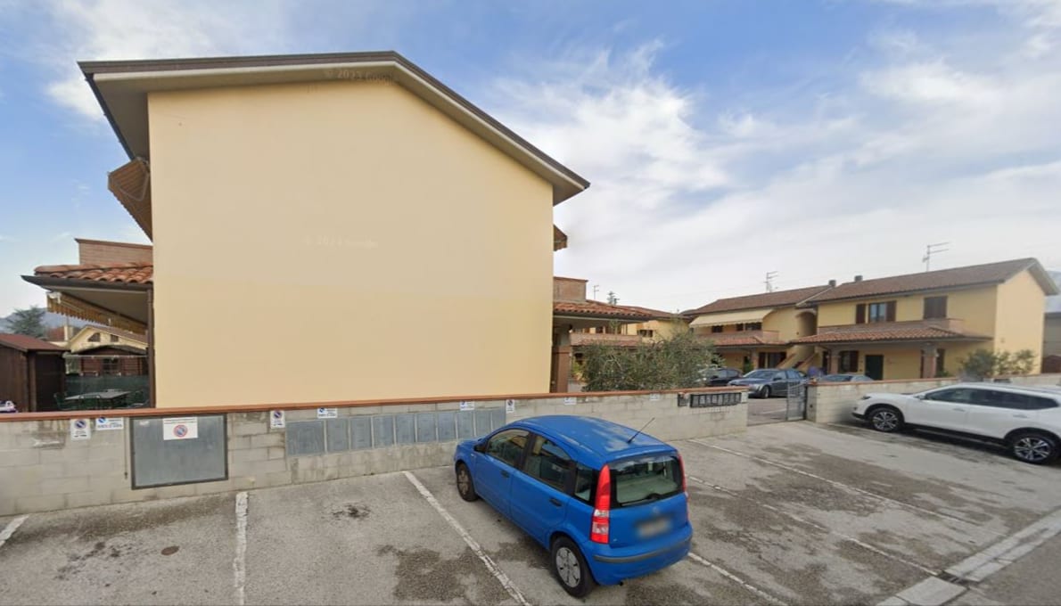 La testata cieca di un blocco di Quartiere U e il parcheggio interno del complesso.