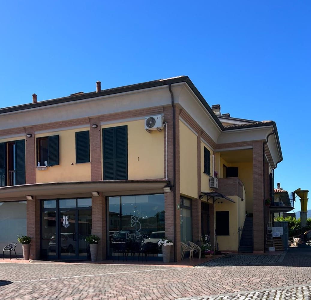 Residence Romana: il fronte d’angolo con i pilastri in laterizio e le vetrine del fondo commerciale.