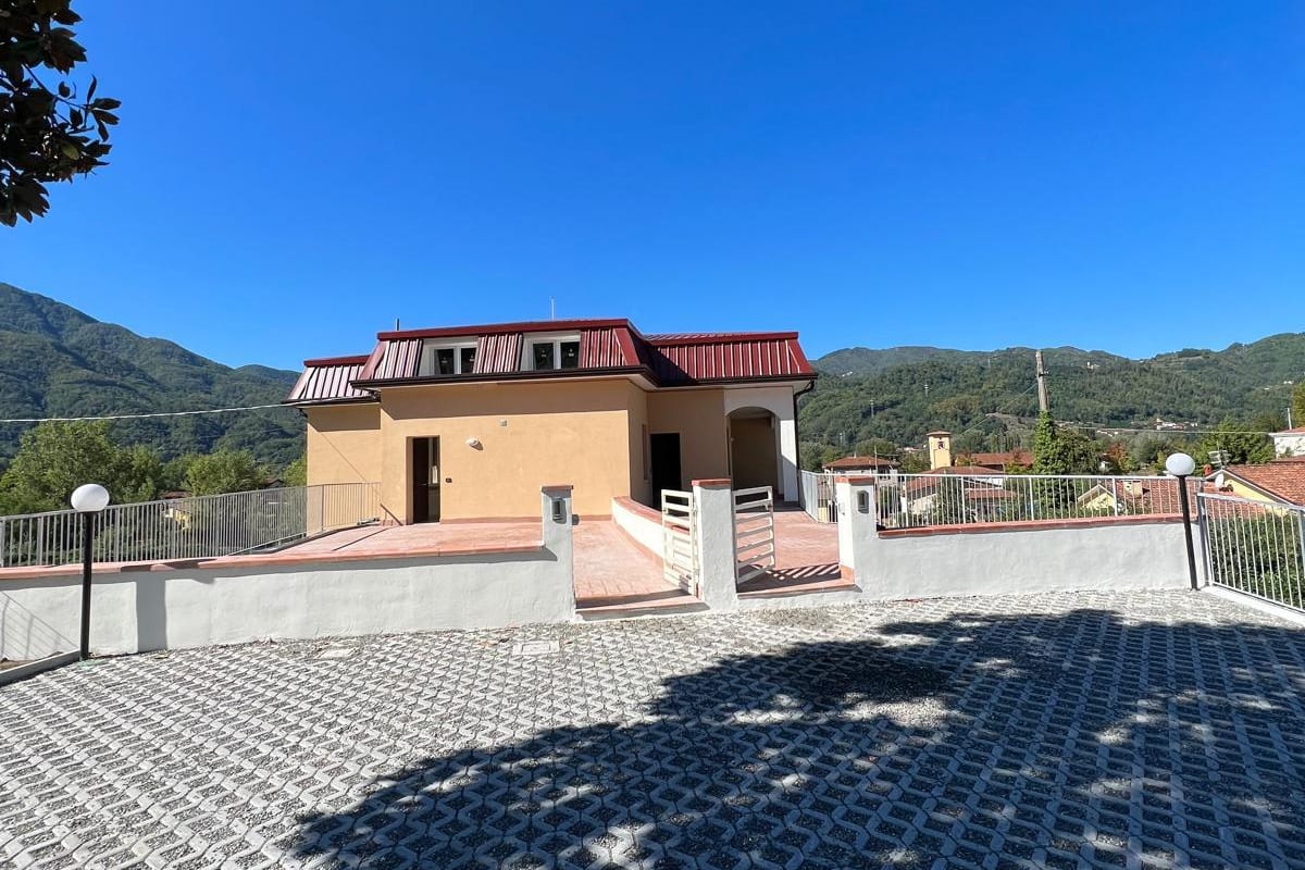 Villa Benedetta conclusa, con il tetto in lamiera rossa e le colline della Valle del Serchio sullo sfondo.