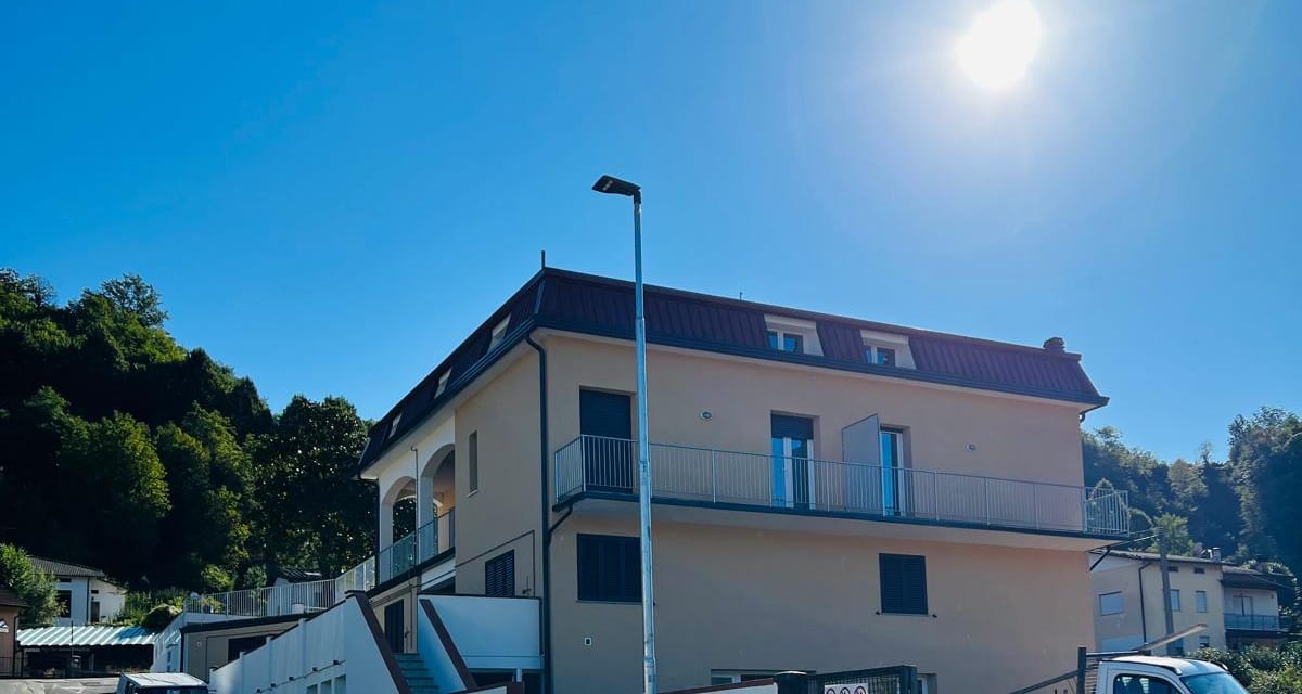 Villa Benedetta dalla strada: il volume a tre piani con le logge ad arco e il bosco alle spalle.