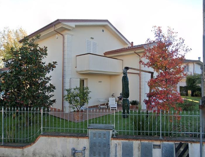 Villa Vittoria dal fianco, con il balcone coperto e il giardino piantumato lungo la recinzione.