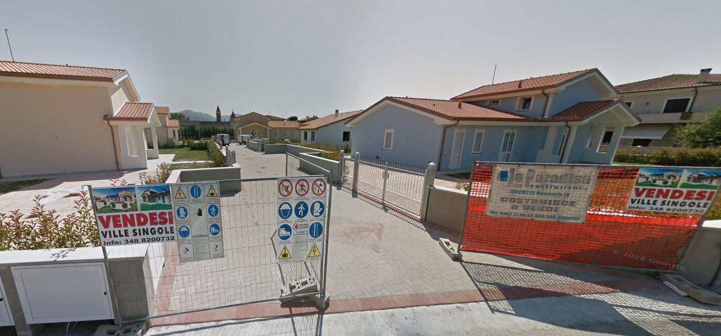 L’ingresso pedonale di Ville Corniglia durante la commercializzazione, con i cartelli di vendita affissi alla recinzione.