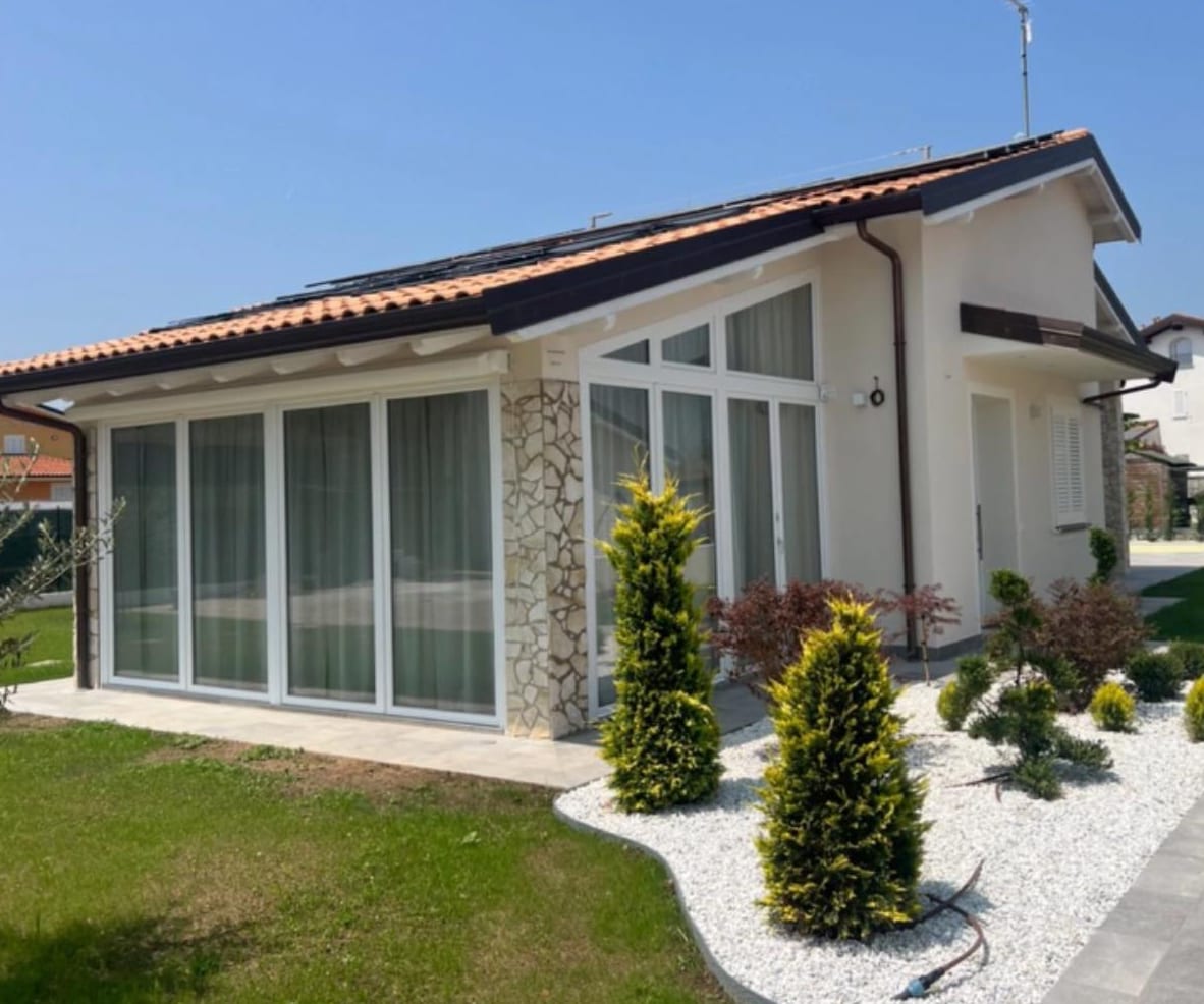 Ville Gemini a lavori conclusi: la veranda vetrata, il rivestimento in pietra e il giardino sistemato.